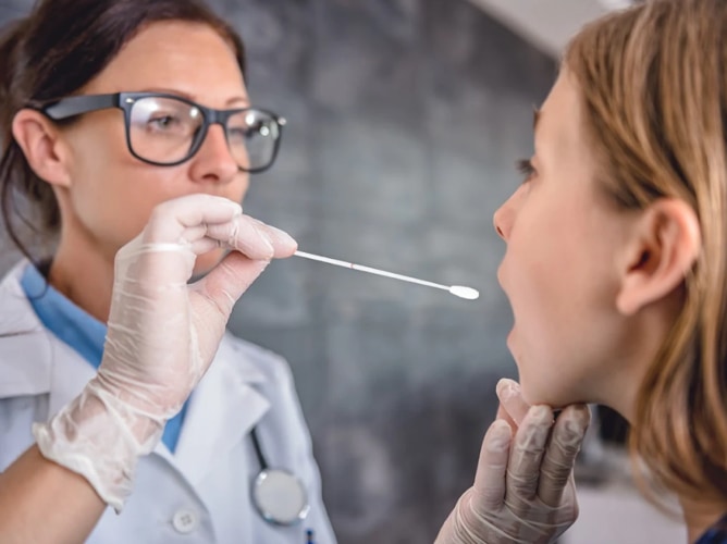 female doctor swabbing throat for flu or COVID